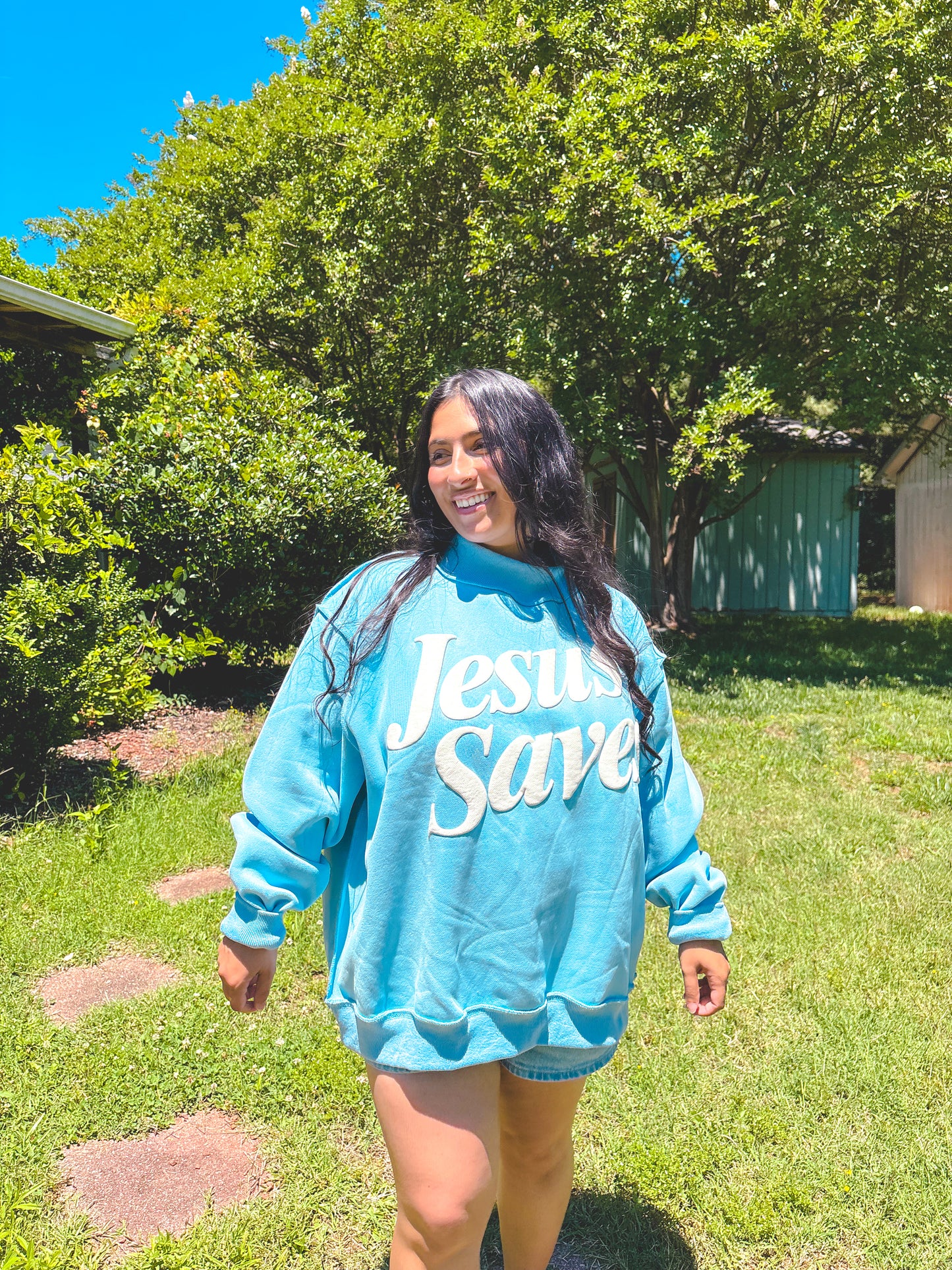 Person wearing a blue sweatshirt with 'Jesus Save' text outdoors.