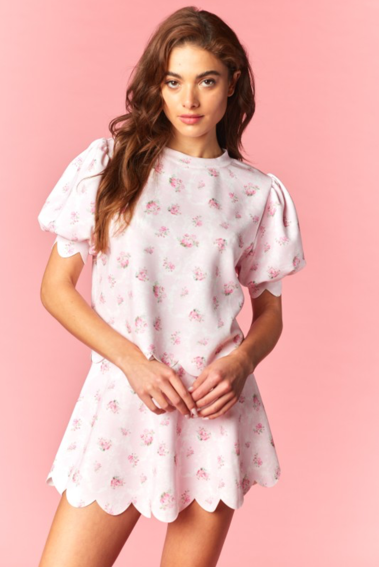 Woman wearing a pink skort set with pink floral pattern against a pink background