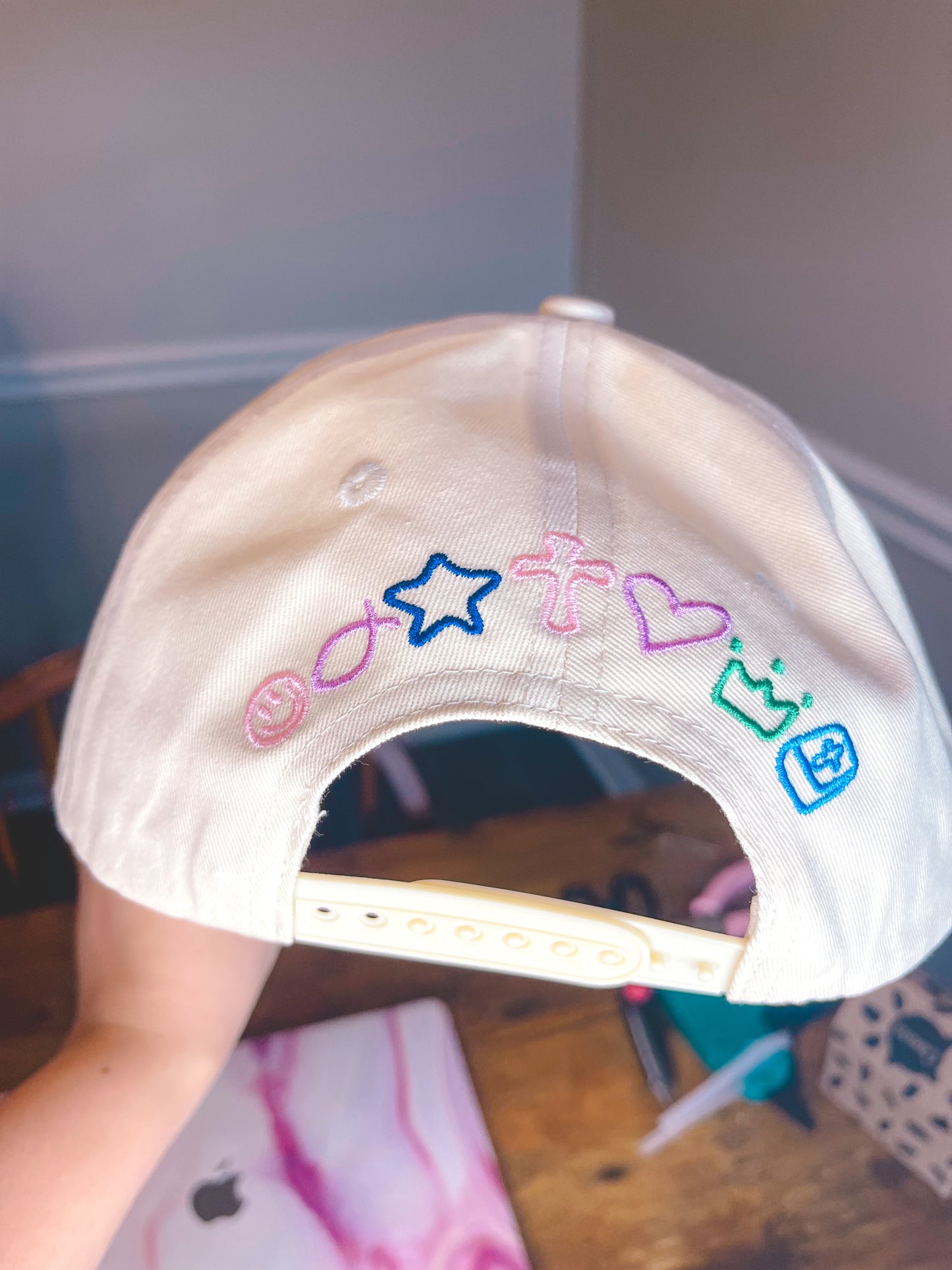 Beige cap with colorful embroidered designs on a blurred indoor background
