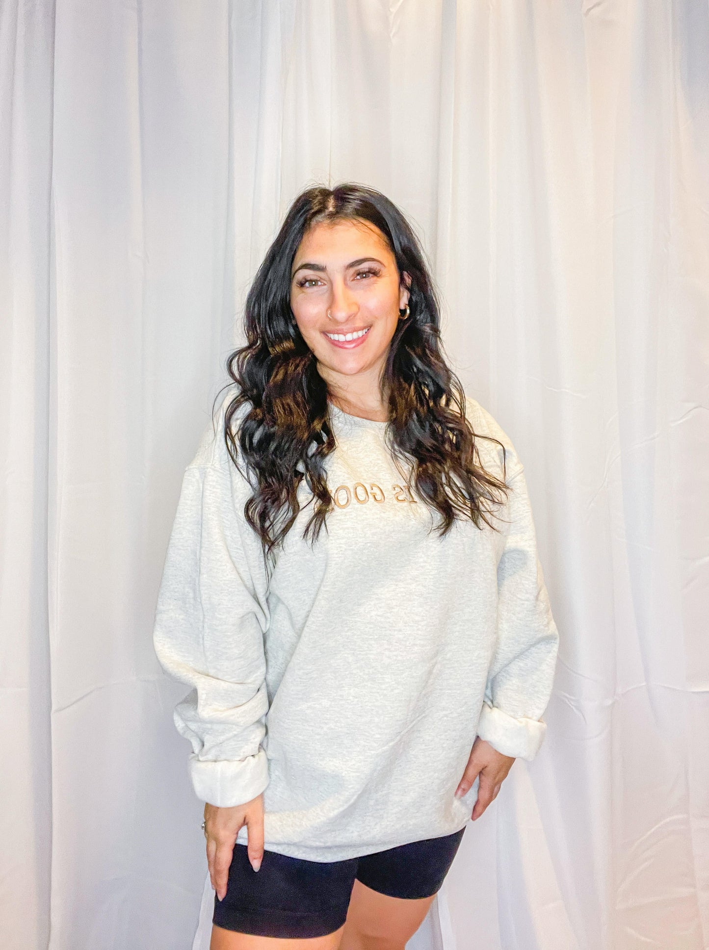 A soft and comfy light grey crewneck sweatshirt with God is Good embroidered on the front.