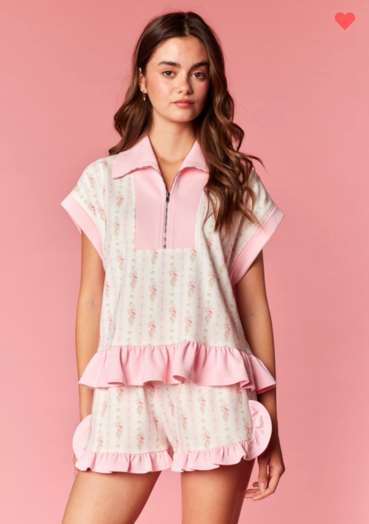Woman wearing a pink and white outfit with ruffled details on a pink background