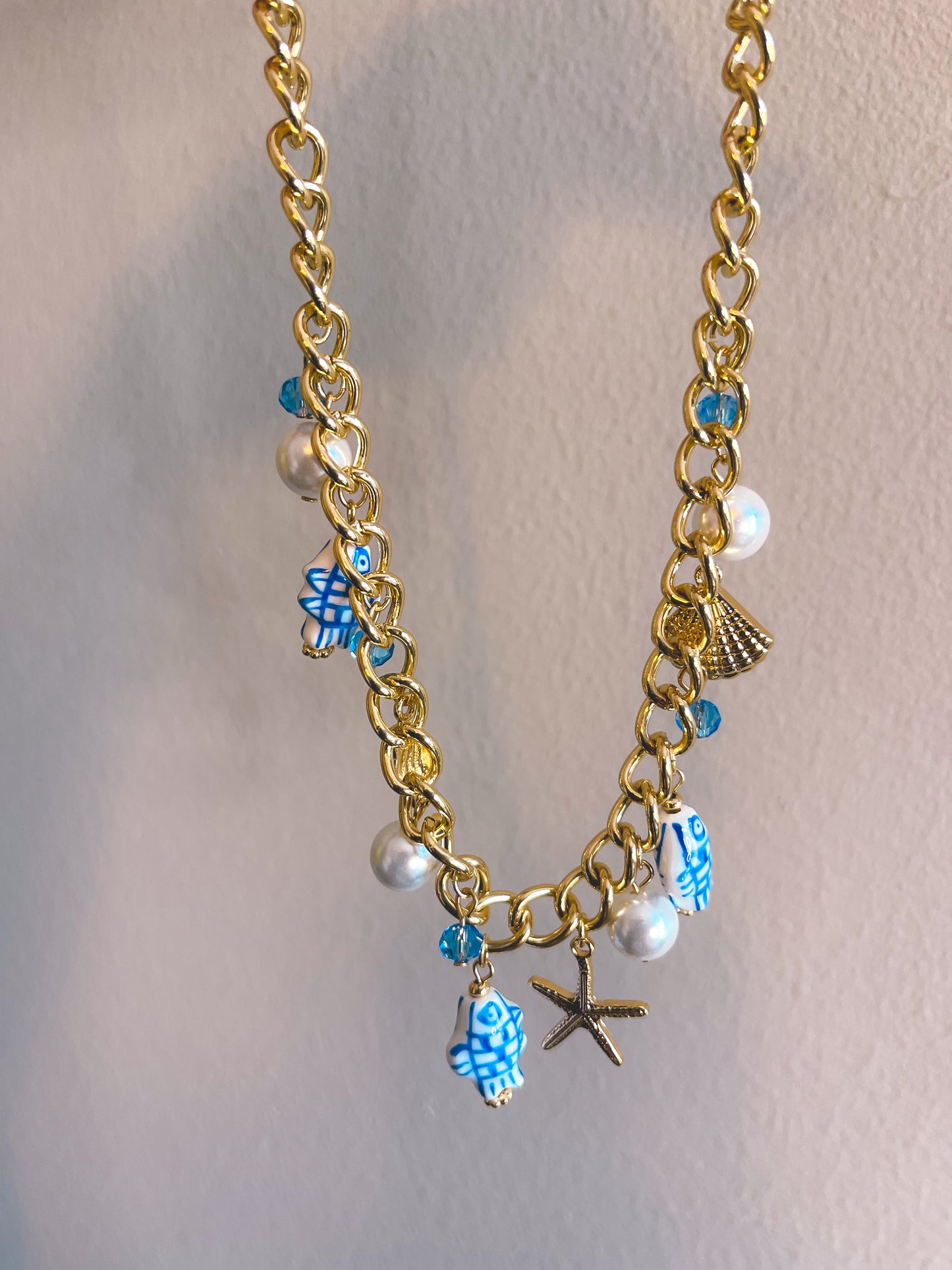 Gold necklace with various charms on a light gray background