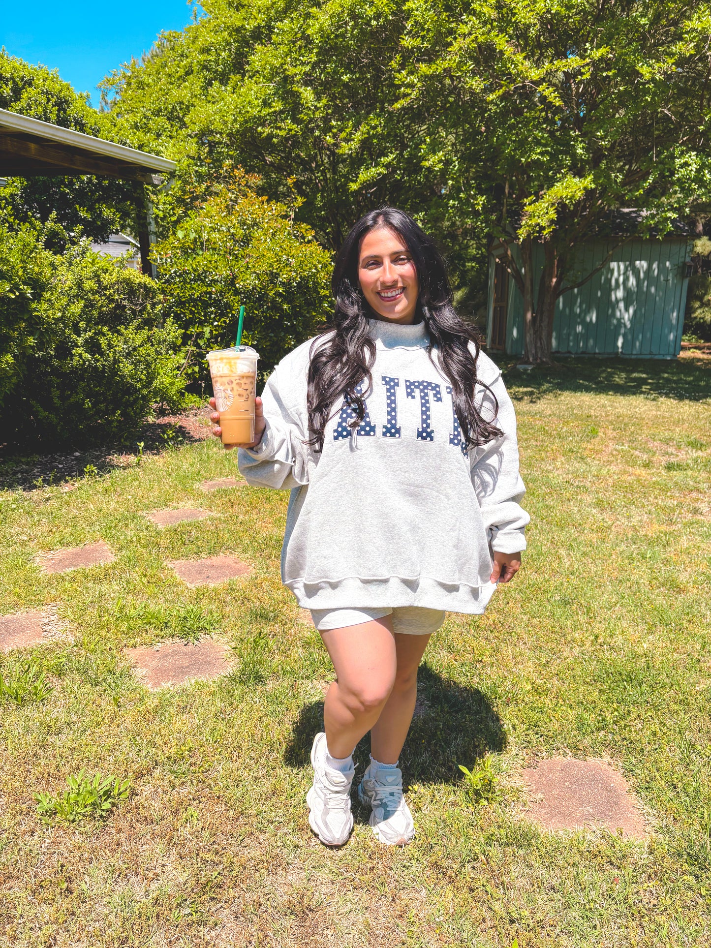 Person holding a drink outdoors with trees in the background
