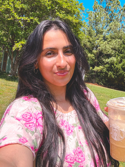 Woman holding a Starbucks cup outdoors with trees in the background
