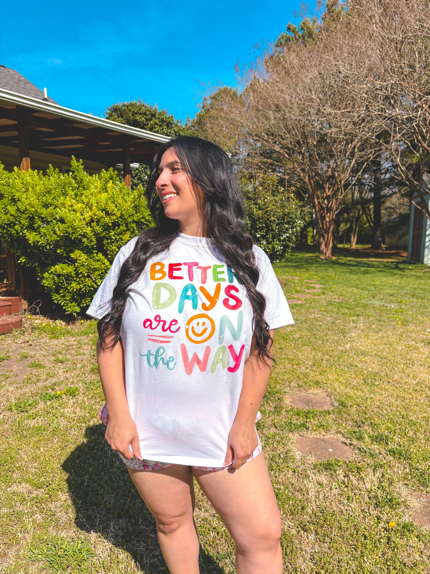 Person wearing a white t-shirt with colorful text in an outdoor setting