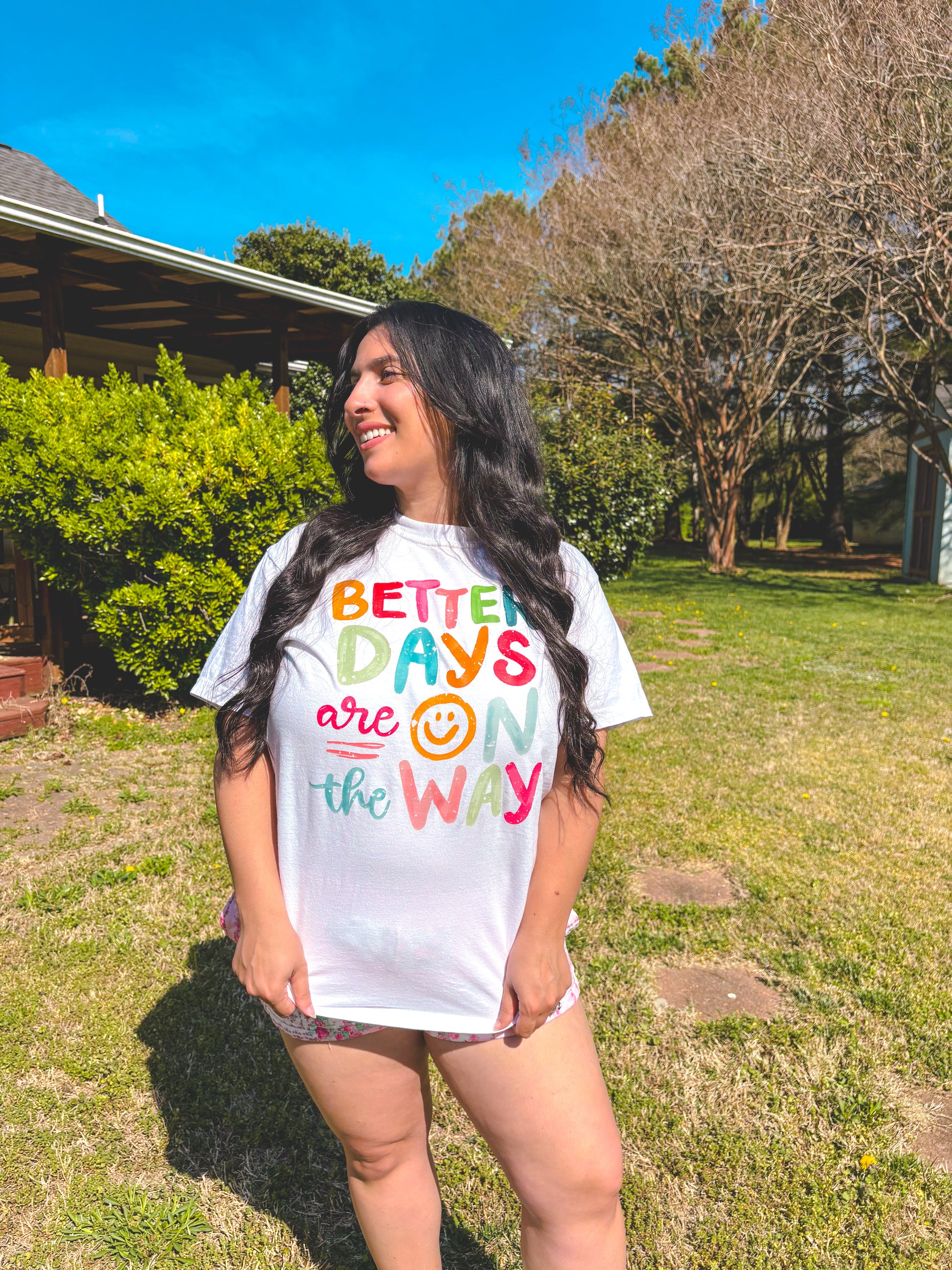 Person wearing a white t-shirt with colorful text in an outdoor setting