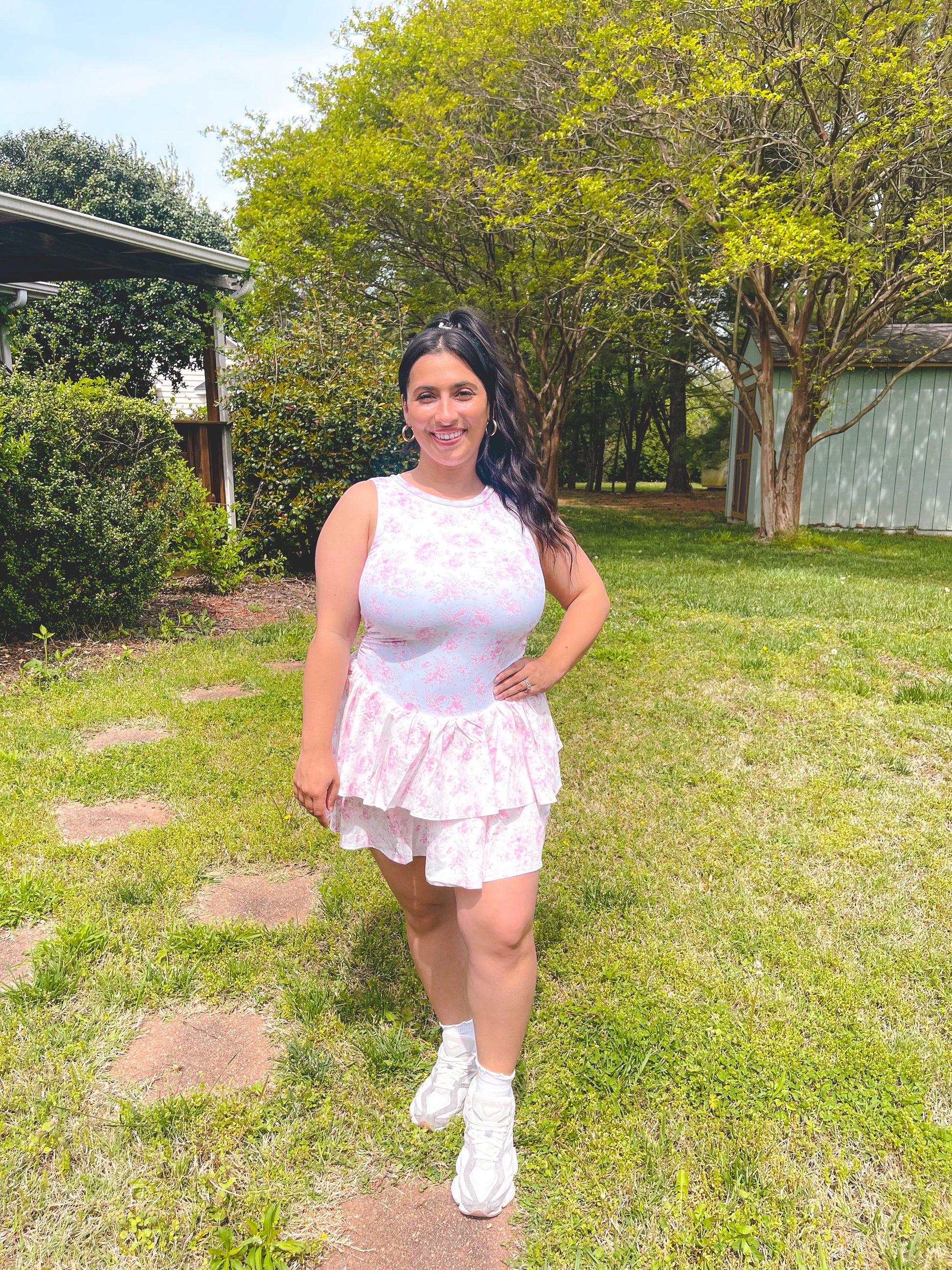 Woman in a white dress standing in a grassy area with trees in the background