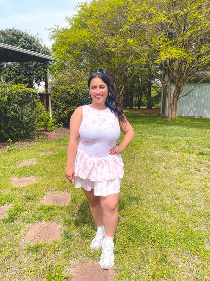 Woman in a white dress standing in a grassy area with trees in the background