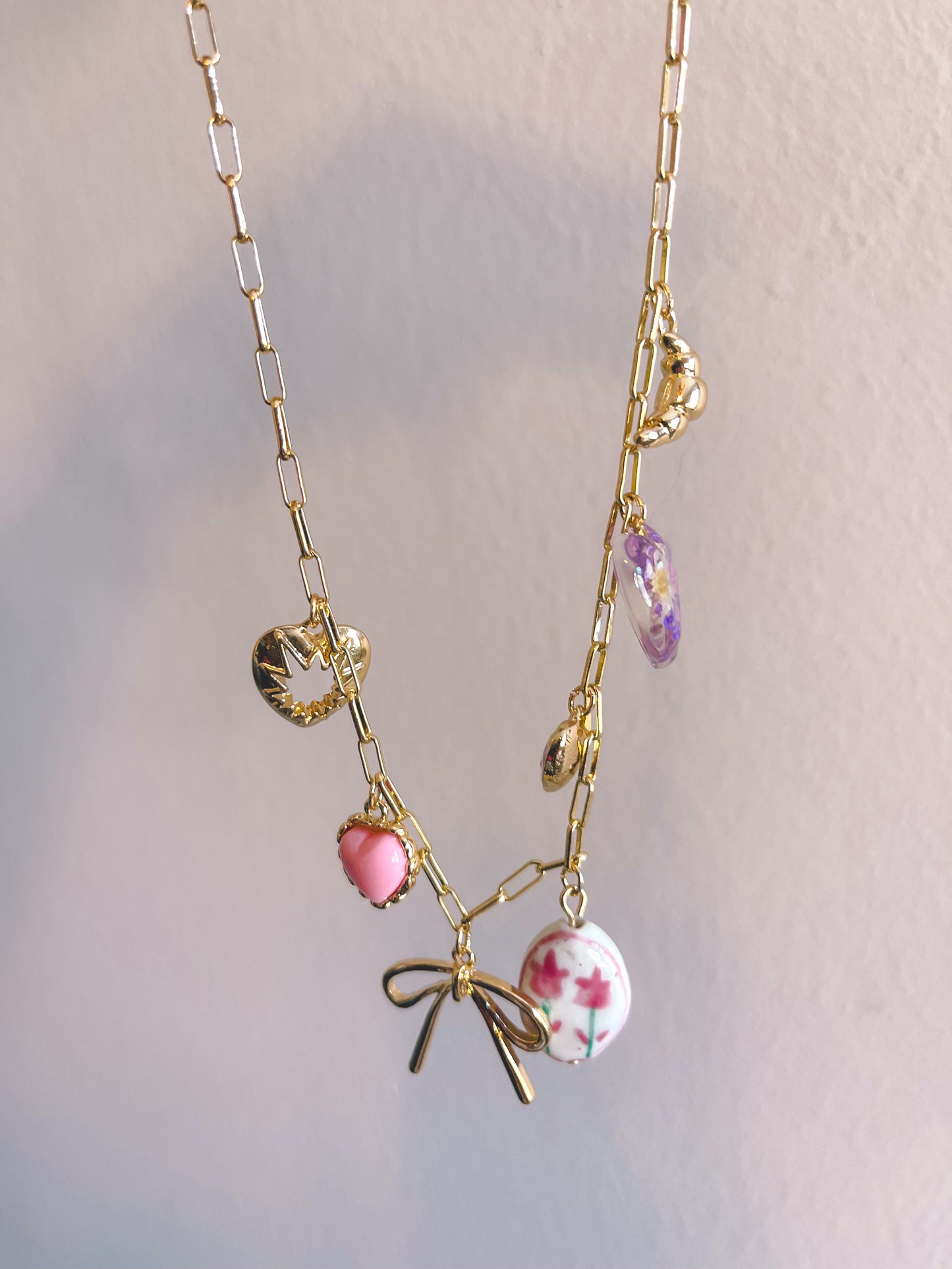 Gold necklace with colorful charms on a light gray background