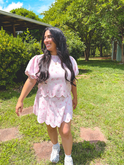 Woman in a pink floral dress standing outdoors on a sunny day