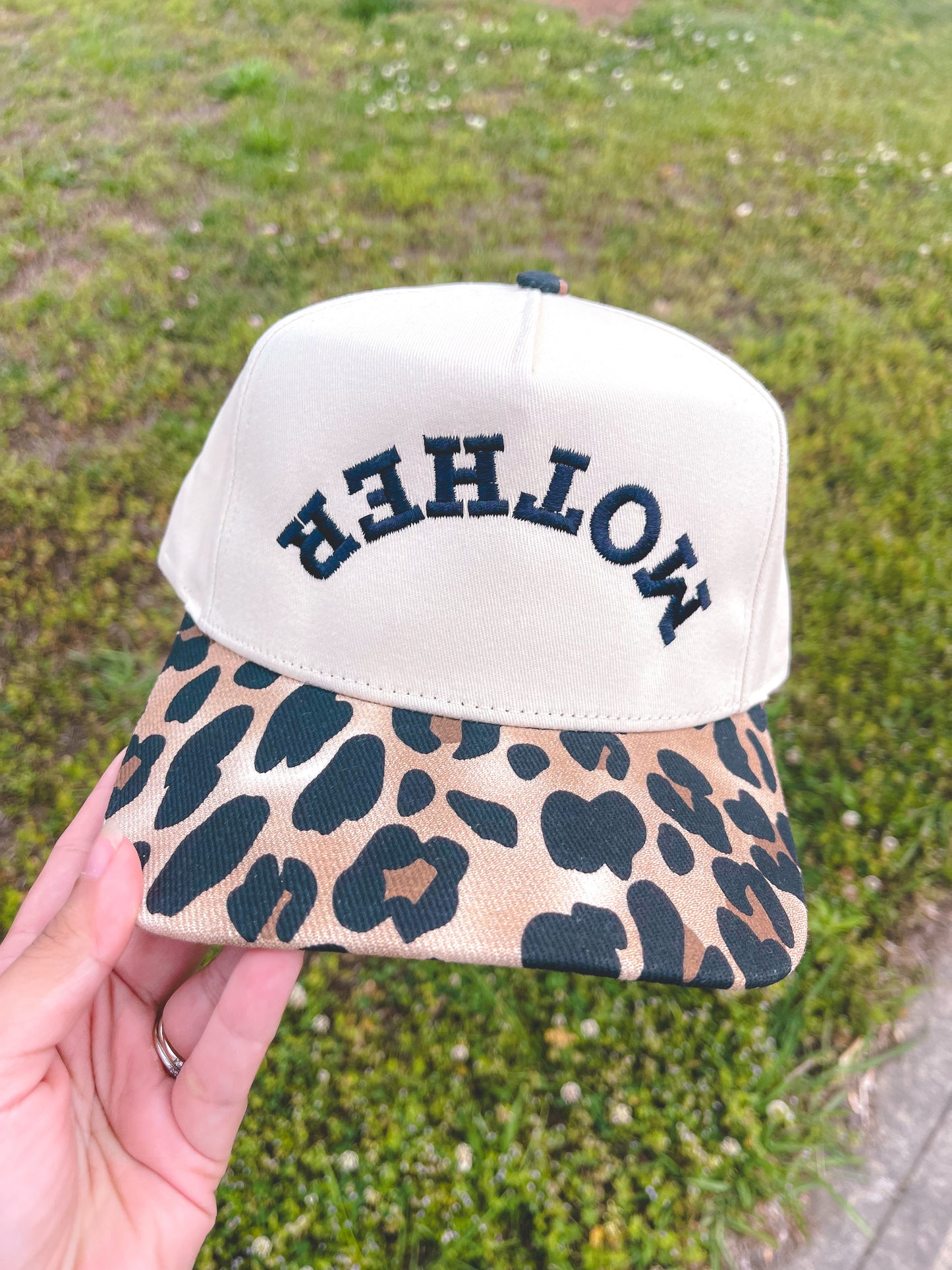 Cap with leopard print visor and 'MOTHER' text on a grassy background