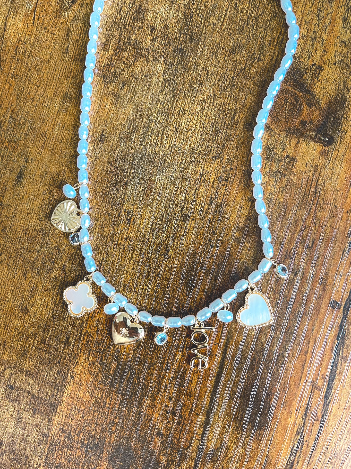 Necklace with blue beads and heart-shaped charms on a wooden surface
