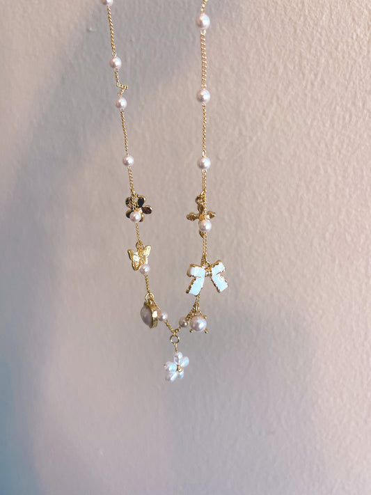 Necklace with floral and butterfly pendants on a light background