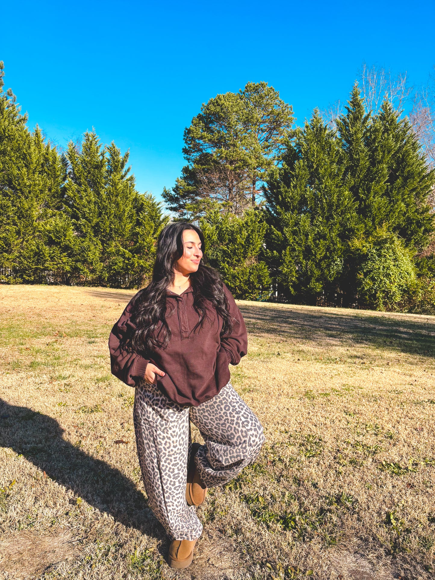 Cozy brown sweatshirt and leopard print wide-leg pants outfit in a grassy outdoor setting.