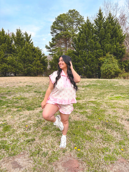 Woman in a pink outfit standing in a grassy field with trees in the background