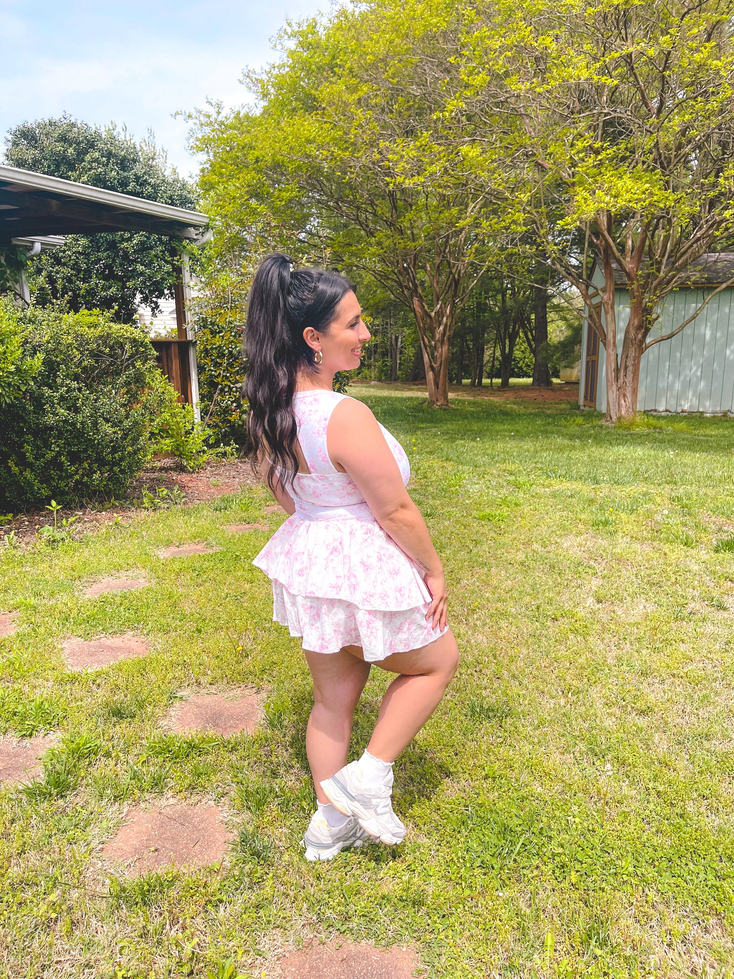 Woman in a white dress standing in a grassy area with trees in the background