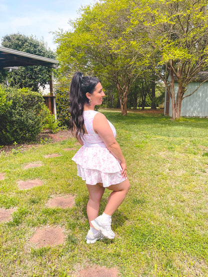 Woman in a white dress standing in a grassy area with trees in the background