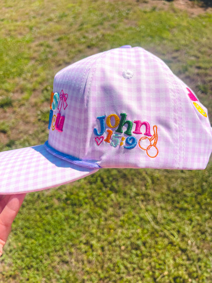 Purple checkered cap with colorful text and designs on a grassy background
