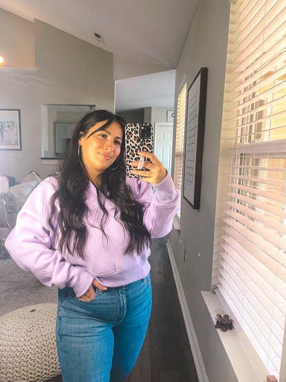 Person wearing a purple hoodie and blue jeans taking a mirror selfie in a room.