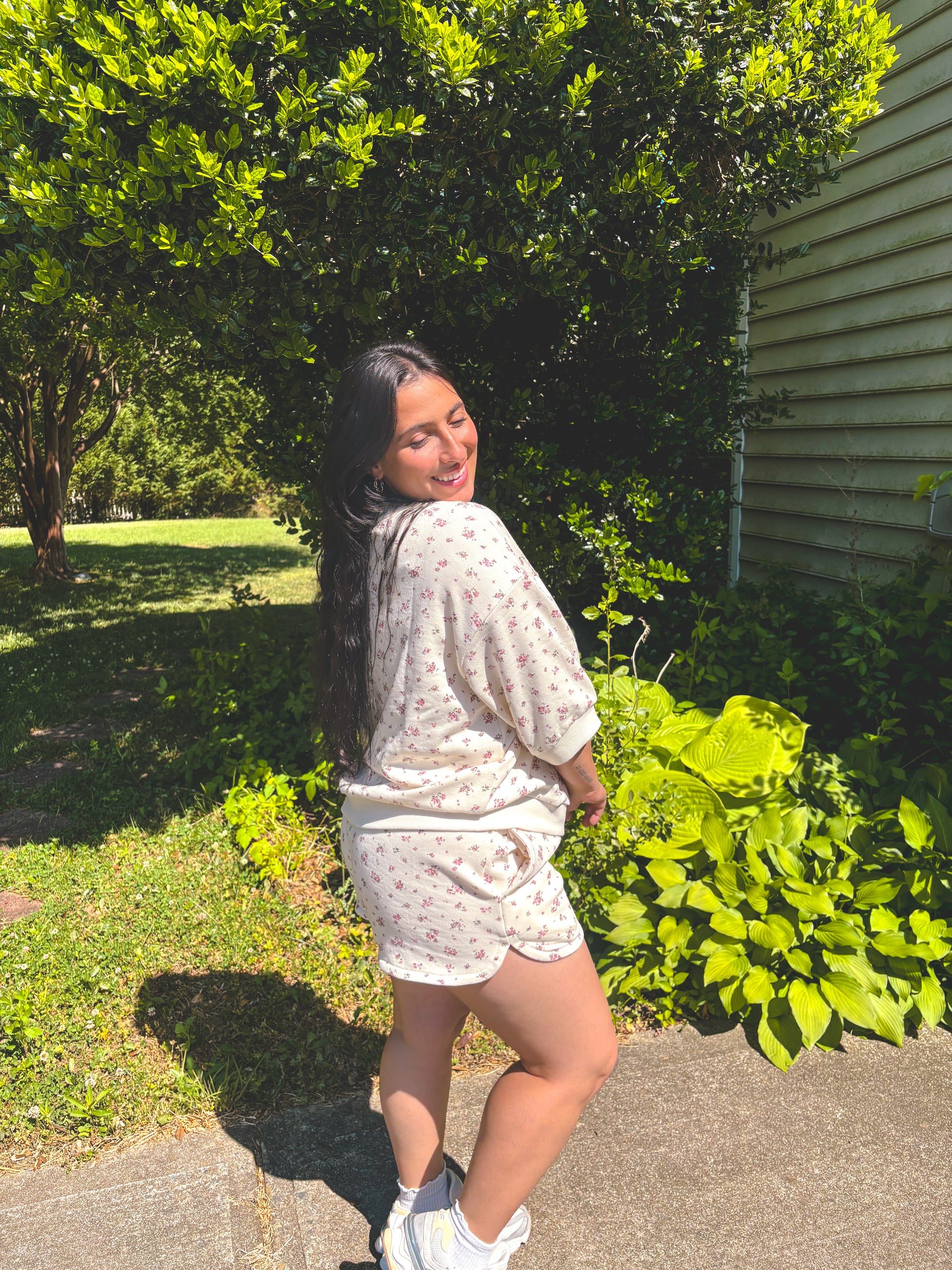 Girl standing in front of bush in floral shorts set