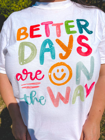White t-shirt with colorful text 'Better Days are on the Way' featuring a smiley face.