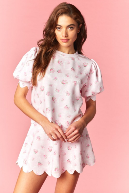 Woman wearing a pink skort set with pink floral pattern against a pink background