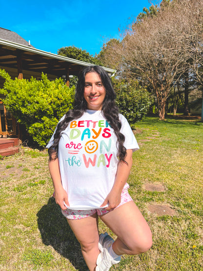 Person wearing a colorful 'Better Days are on the Way' shirt outdoors.