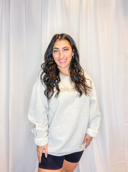 A soft and comfy light grey crewneck sweatshirt with God is Good embroidered on the front.